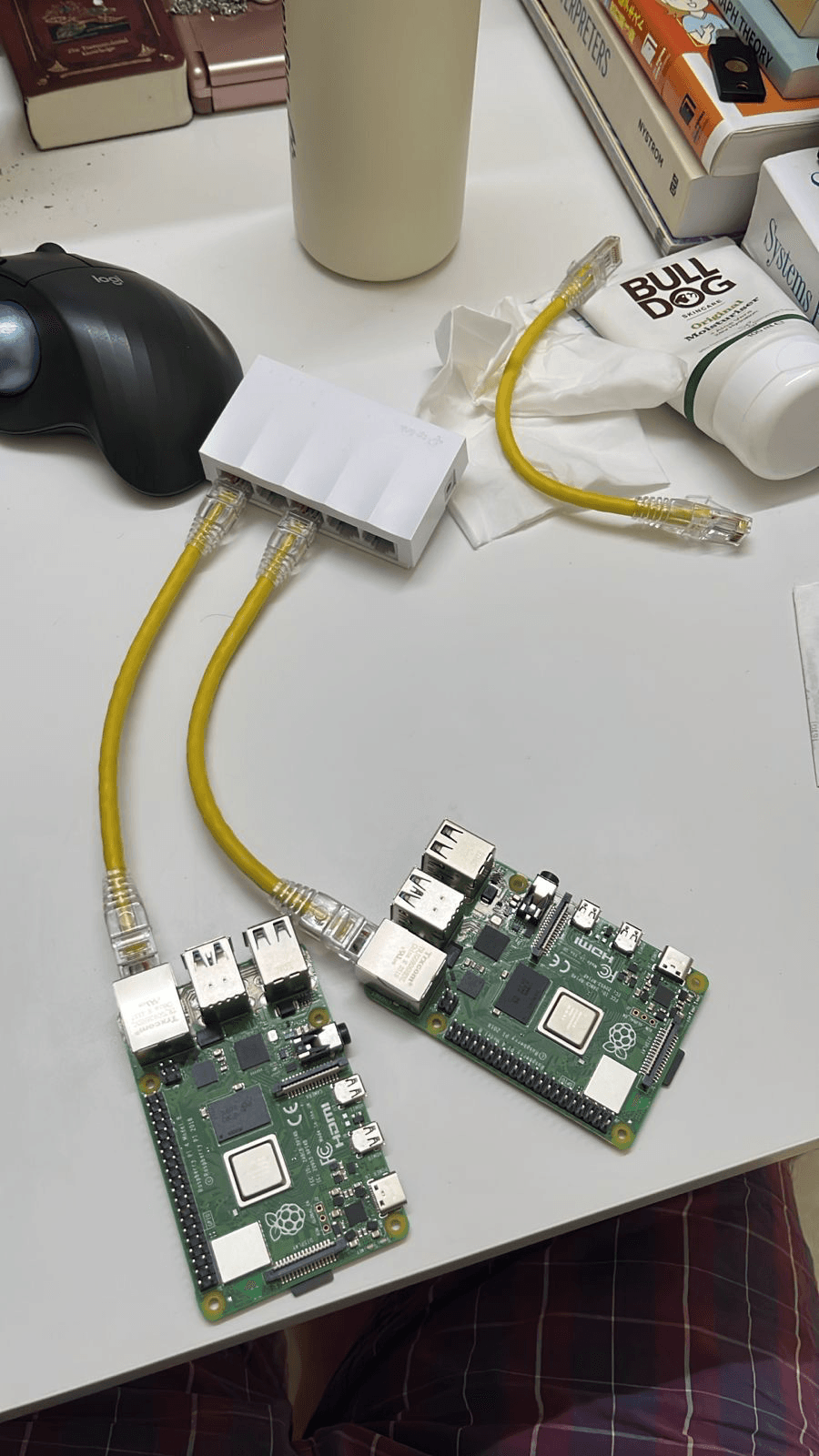 My basic Raspberry Pi network - Two Raspberry Pi 4s connected to a small white desktop ethernet switch with short yellow ethernet cables